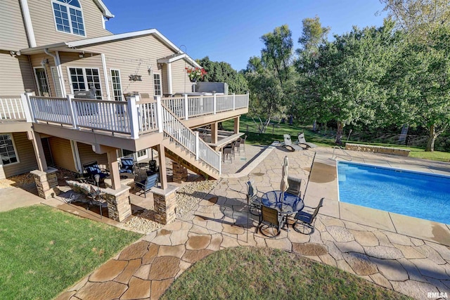 view of pool featuring a fire pit, a patio area, a wooden deck, and a lawn