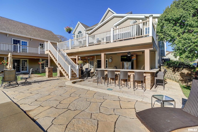 rear view of house with ceiling fan, exterior bar, and a patio