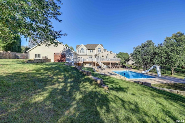 view of pool with a patio area, a lawn, a wooden deck, and a water slide