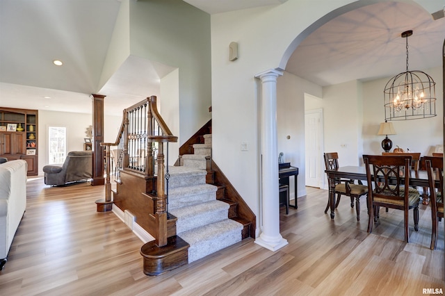 stairway featuring hardwood / wood-style floors, decorative columns, and a chandelier