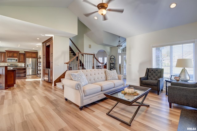 living room with ceiling fan, light hardwood / wood-style floors, and high vaulted ceiling