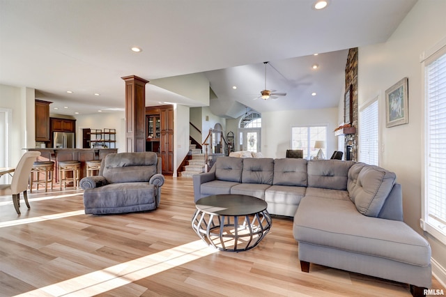 living room featuring decorative columns, light hardwood / wood-style flooring, ceiling fan, and lofted ceiling