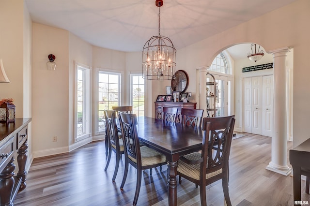 dining area with decorative columns, a chandelier, and hardwood / wood-style flooring