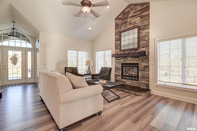 living room featuring a stone fireplace, ceiling fan, plenty of natural light, and hardwood / wood-style flooring