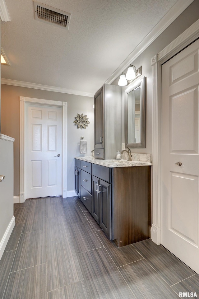 bathroom featuring a textured ceiling, vanity, and crown molding