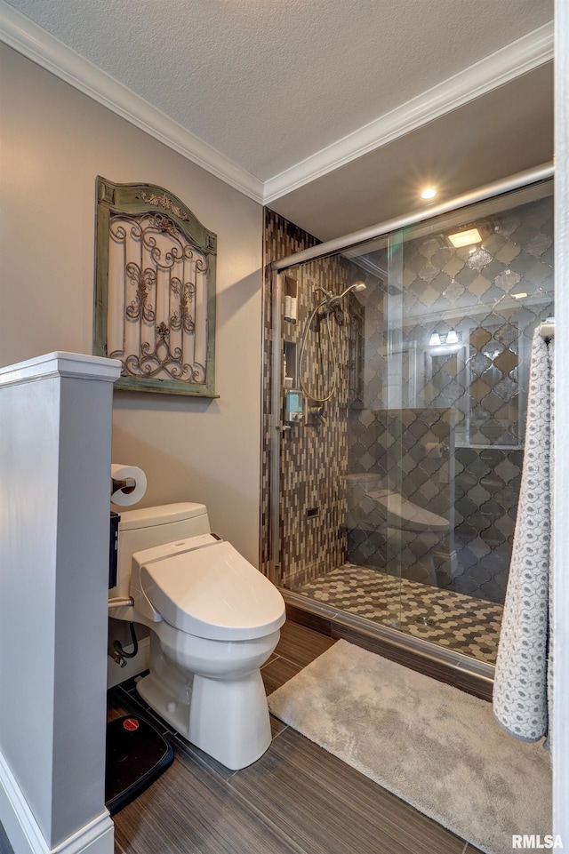 bathroom with ornamental molding, a textured ceiling, toilet, and a shower with shower door