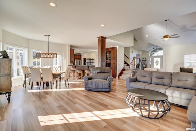 living room with ceiling fan, vaulted ceiling, ornate columns, and light hardwood / wood-style flooring