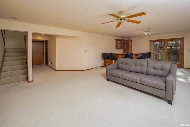 carpeted living room with ceiling fan and bar area