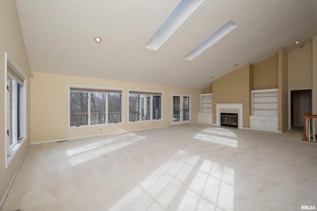 unfurnished living room with light carpet, a skylight, and high vaulted ceiling