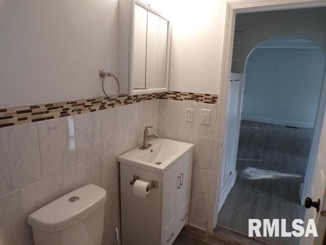 bathroom with hardwood / wood-style floors, vanity, tile walls, and toilet