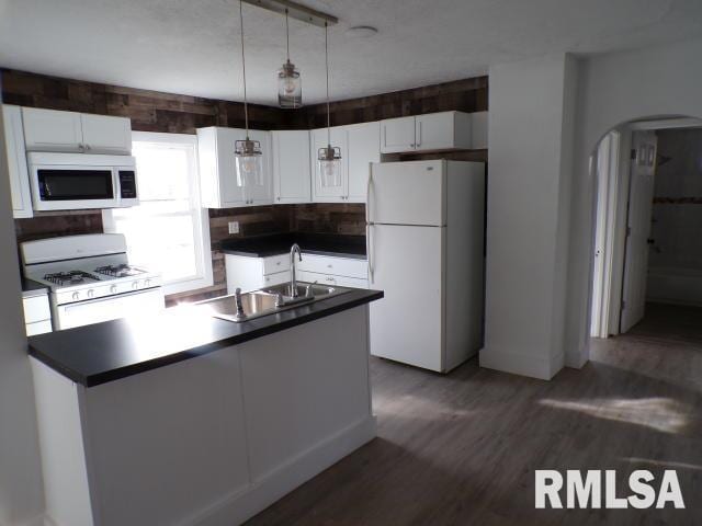 kitchen featuring white cabinetry, sink, dark hardwood / wood-style flooring, pendant lighting, and white appliances