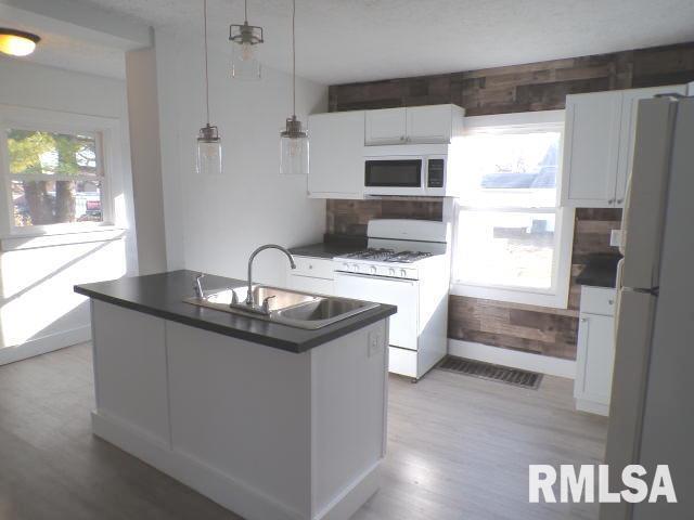 kitchen with plenty of natural light, white cabinetry, and white appliances