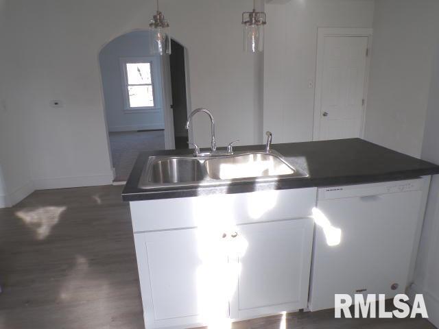 kitchen featuring pendant lighting, dishwasher, white cabinets, and sink