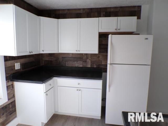 kitchen with tasteful backsplash, white cabinetry, white fridge, and a textured ceiling