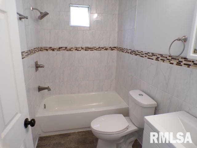 bathroom featuring toilet, tile walls, and tiled shower / bath