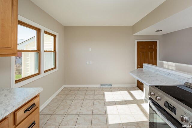 kitchen featuring stainless steel electric range, light tile patterned floors, and a wealth of natural light