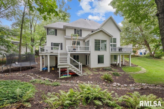 back of house with a lawn, a trampoline, and a wooden deck