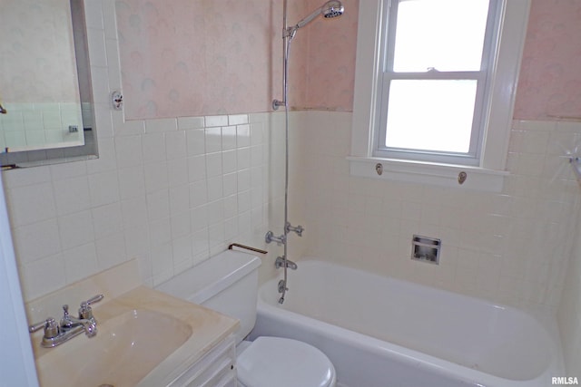 full bathroom featuring vanity, toilet, tiled shower / bath, and tile walls