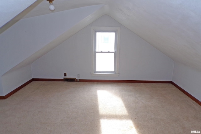 additional living space with light colored carpet and vaulted ceiling