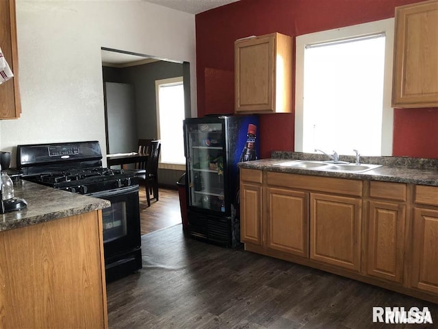 kitchen featuring black gas range oven, dark hardwood / wood-style flooring, and sink