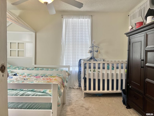 carpeted bedroom featuring ceiling fan and a textured ceiling