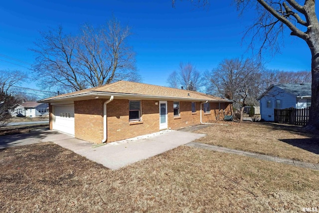 back of house featuring driveway, fence, and brick siding