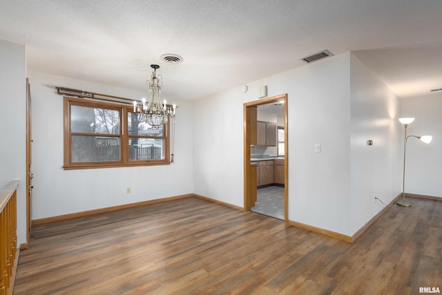 empty room with visible vents, baseboards, and wood finished floors