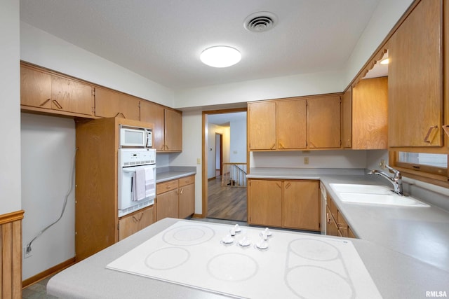 kitchen with visible vents, white appliances, light countertops, and a sink