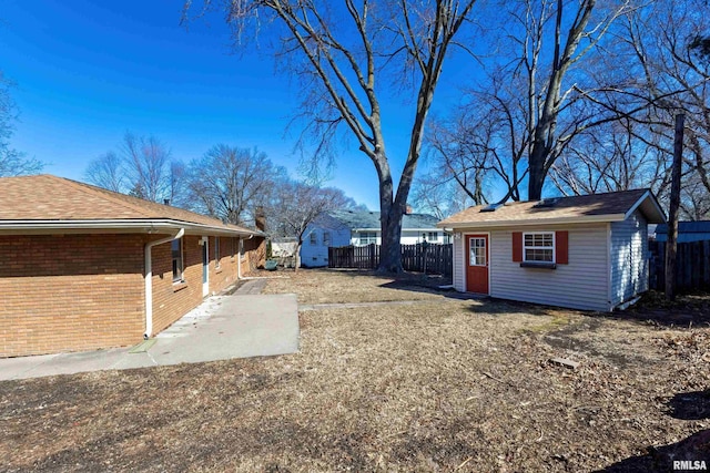 view of yard featuring fence, a patio, and an outbuilding