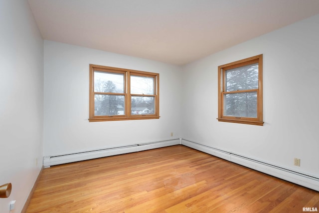 empty room featuring baseboard heating, light wood-type flooring, and a baseboard heating unit