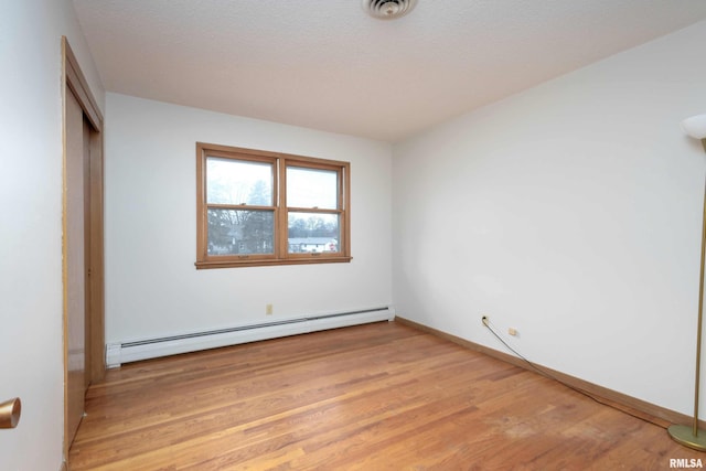 unfurnished bedroom with visible vents, baseboards, light wood-style flooring, a closet, and a baseboard radiator