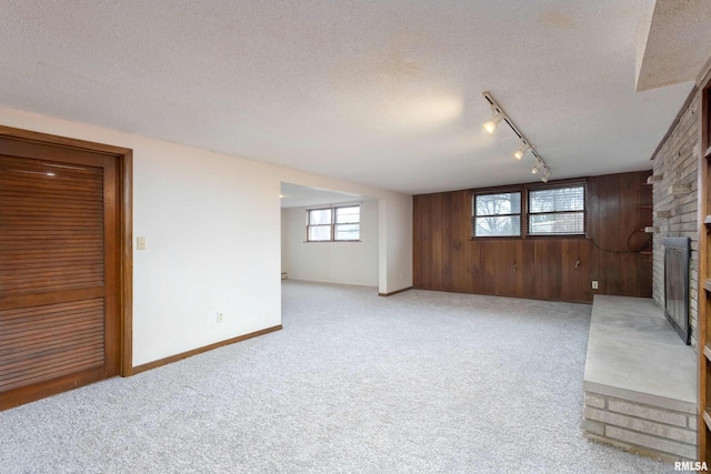 below grade area featuring a large fireplace, light colored carpet, wood walls, and a textured ceiling