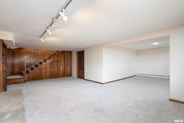 finished below grade area with wooden walls, stairs, carpet floors, a textured ceiling, and a baseboard radiator