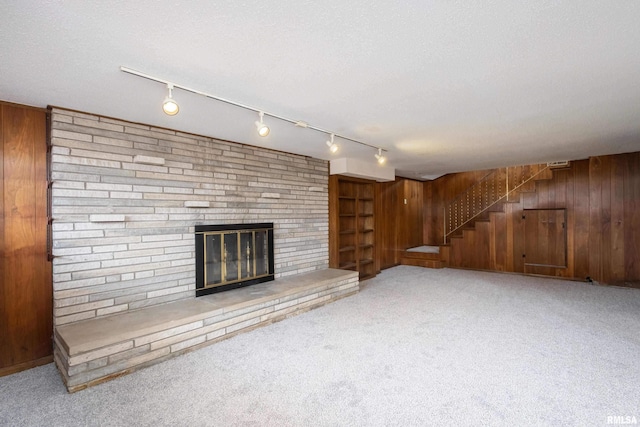 unfurnished living room featuring carpet, wood walls, and a textured ceiling