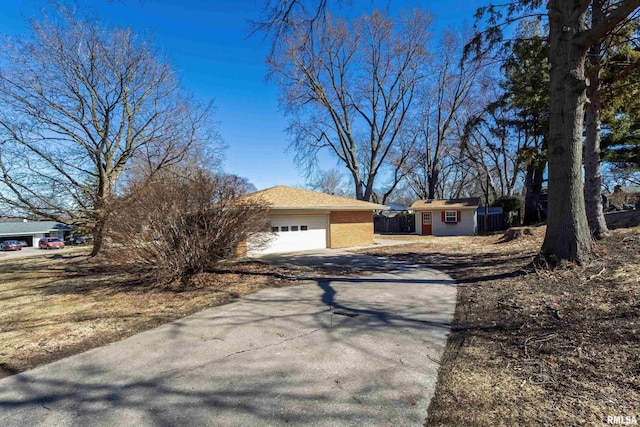 view of front of property with an outdoor structure, concrete driveway, an attached garage, and fence