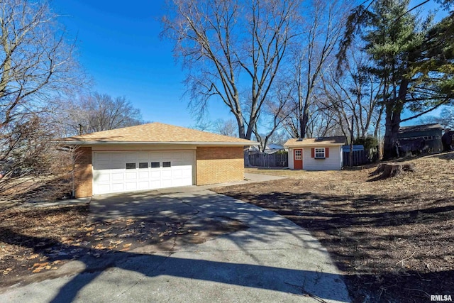 view of side of home with fence, an outdoor structure, concrete driveway, a garage, and brick siding