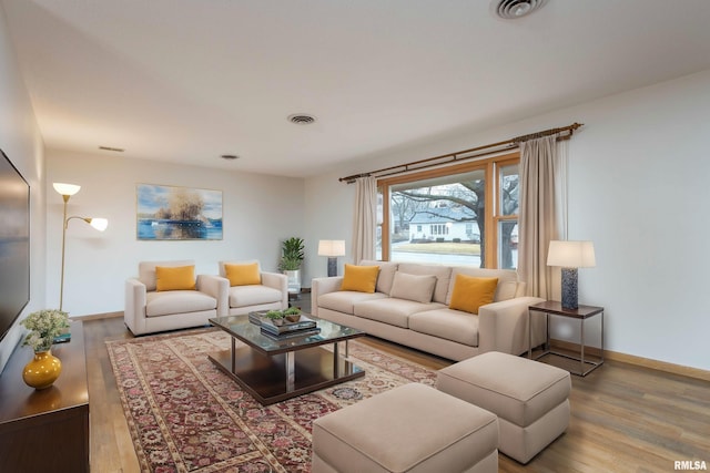 living area featuring wood finished floors, visible vents, and baseboards