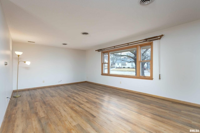 empty room featuring visible vents, baseboards, and wood finished floors