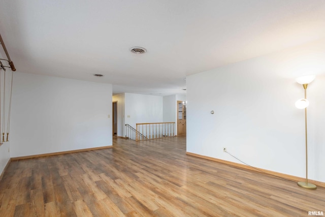 empty room featuring visible vents, baseboards, and wood finished floors