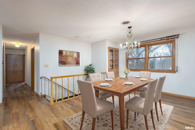 dining room featuring visible vents, baseboards, wood finished floors, and a chandelier