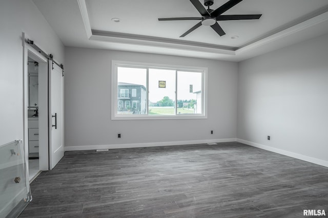 1915 E 59th Ct, Davenport, IA 52807 - unfurnished bedroom with a raised ceiling, a barn door, dark wood-style flooring, and a ceiling fan