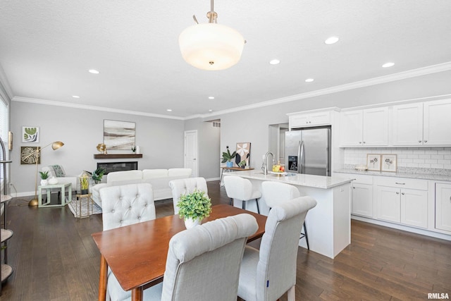 dining room with sink, dark wood-type flooring, and ornamental molding