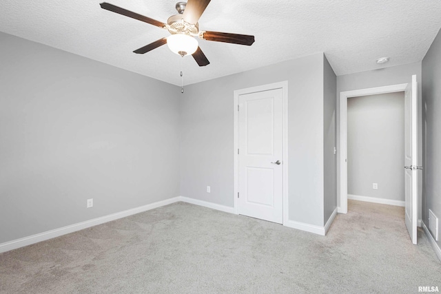 unfurnished bedroom featuring ceiling fan, light colored carpet, and a textured ceiling