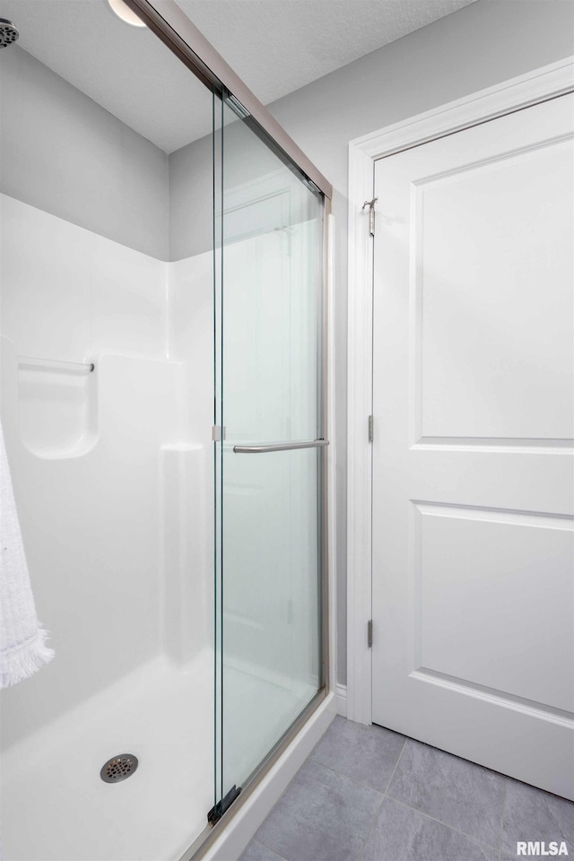 bathroom with tile patterned flooring, an enclosed shower, and a textured ceiling