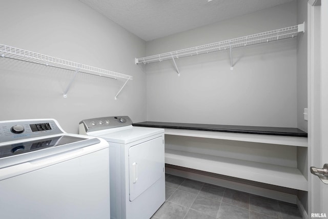 washroom with independent washer and dryer, a textured ceiling, and light tile patterned floors