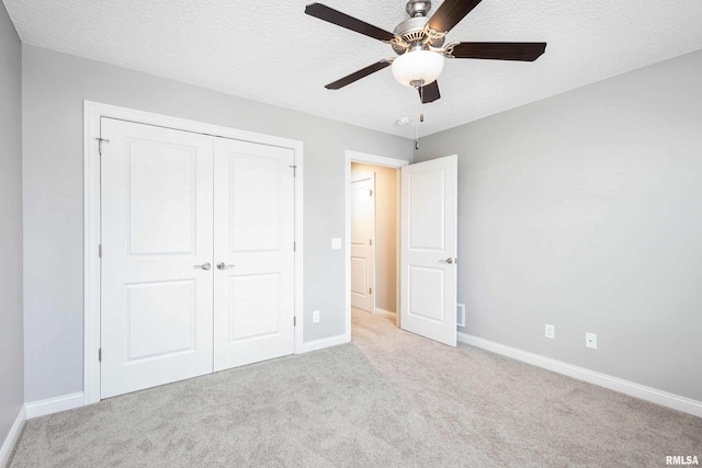 unfurnished bedroom featuring light carpet, a textured ceiling, a closet, and ceiling fan