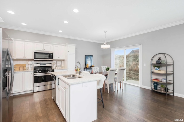 kitchen featuring pendant lighting, white cabinets, a center island with sink, and stainless steel appliances