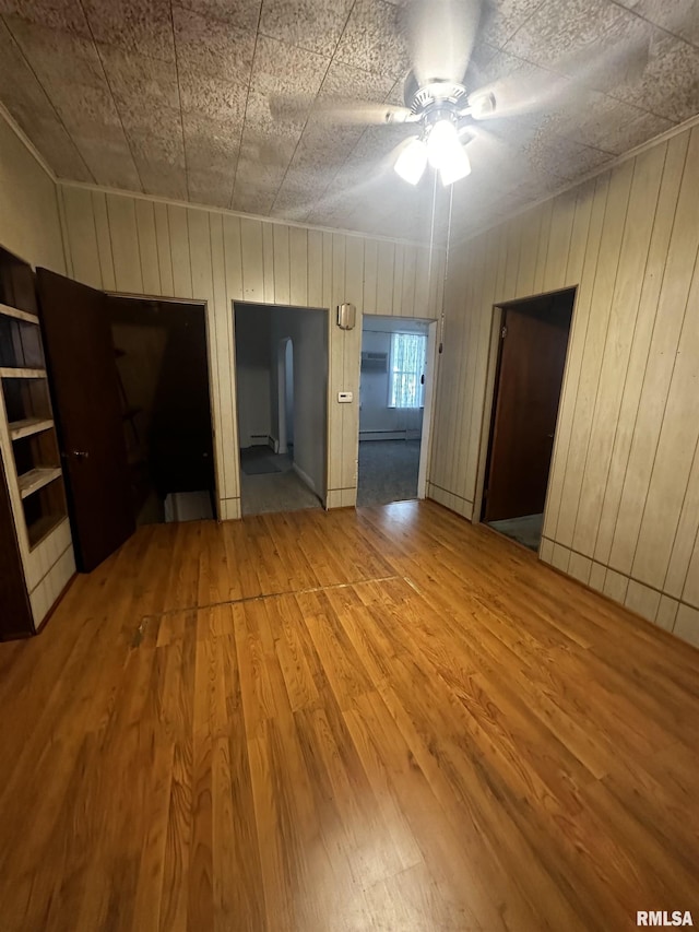 empty room with hardwood / wood-style floors, ceiling fan, and wooden walls