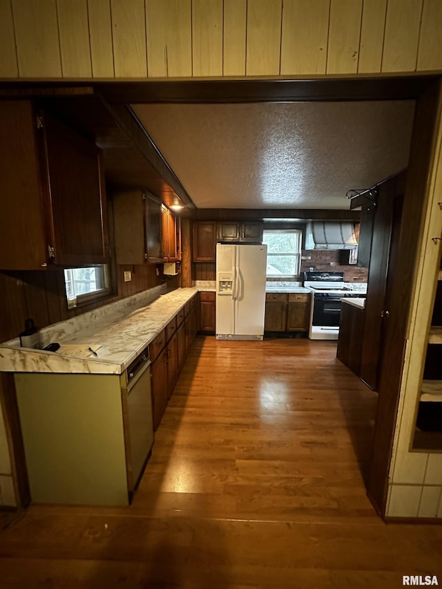 kitchen with hardwood / wood-style floors, white appliances, and range hood