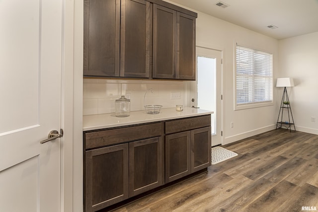 kitchen with tasteful backsplash, dark brown cabinets, and dark wood-type flooring